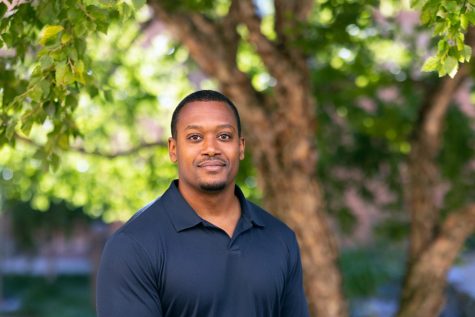 A professional headshot of professor Jason Rodgers. He is outside against greenery, smiling lightly at the camera.