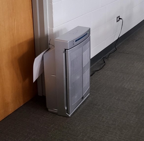 An air purifier from a slight angle. It is a skinny but tall machine, about three feet high and four inches wide.