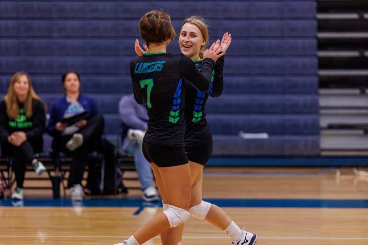Two CLC womens volleyball players high-fiving.
